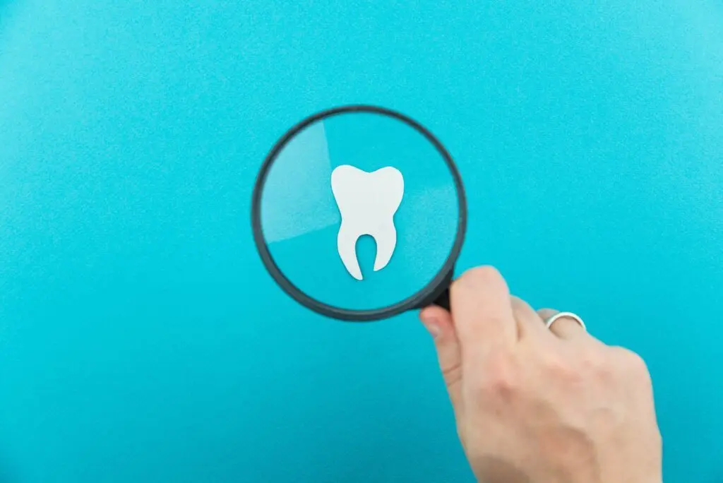 white paper tooth magnifying glass blue background min 1024x684