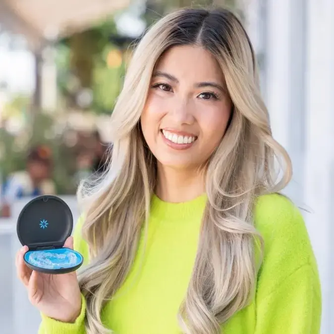 Smiling patient holding Invisalign clear aligners at Meiplus Dentalcare Singapore